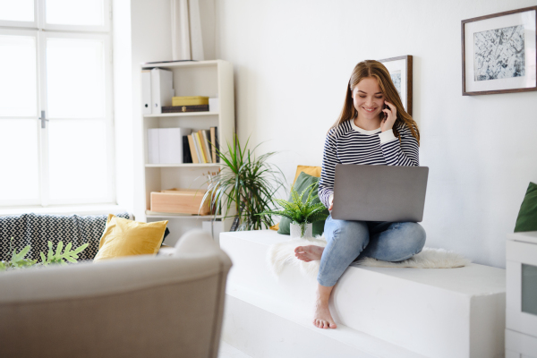 Young woman student with laptop and smartphone working at home, coronavirus concept.