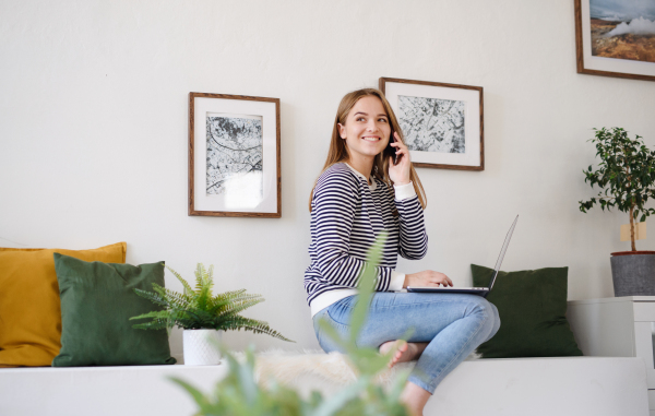 Young woman student with laptop and smartphone working at home, coronavirus concept.