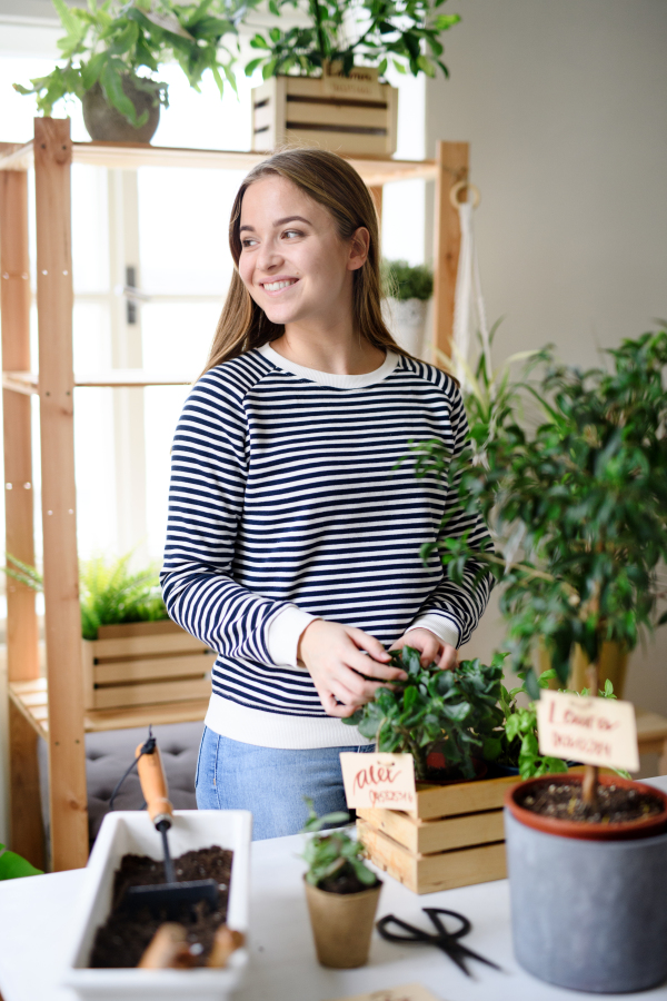 Young woman working at home, plant care concept. Coronavirus concept.