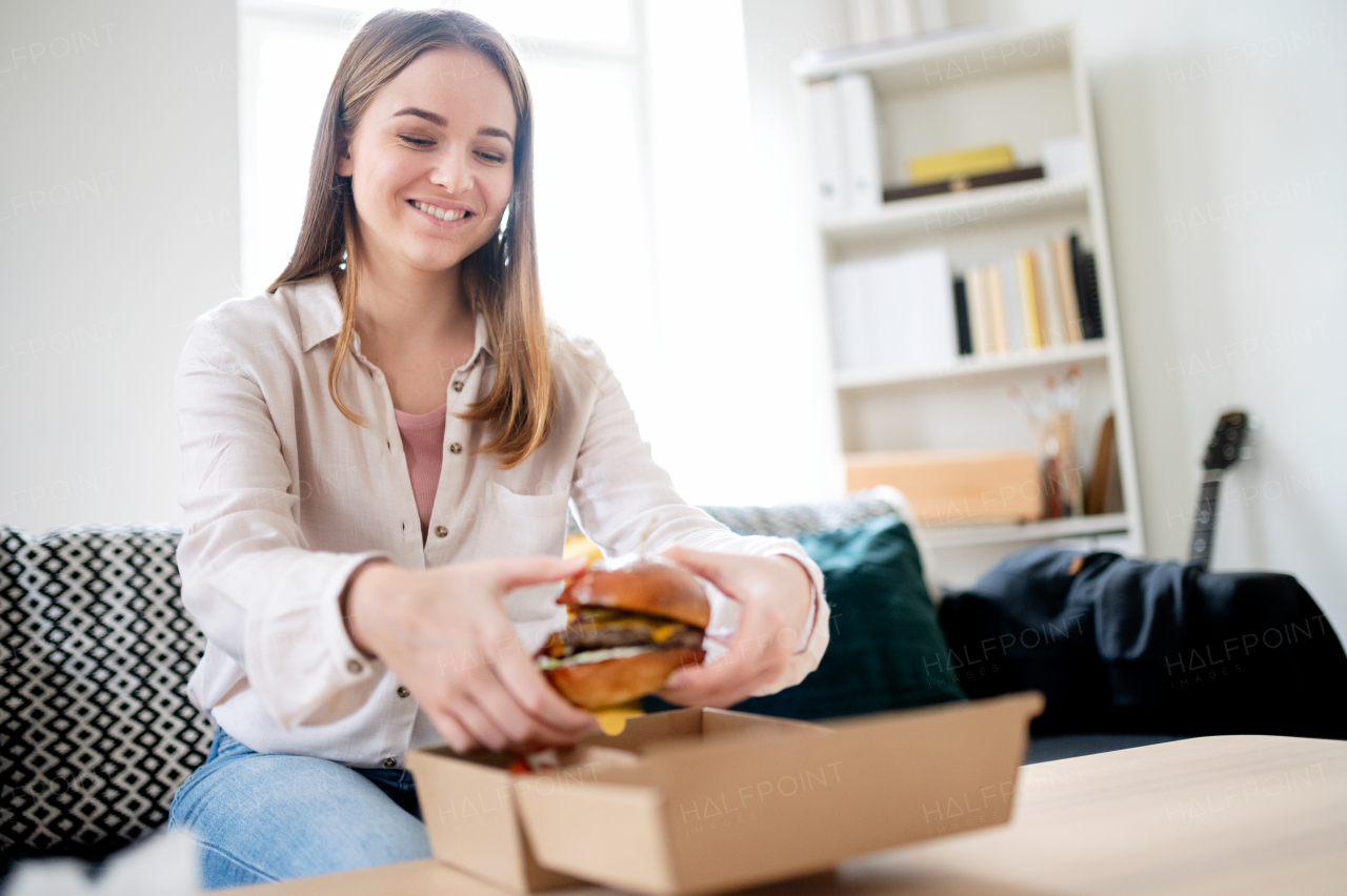 Rear view of young woman with tablet ordering food at home, coronavirus and food delivery concept.