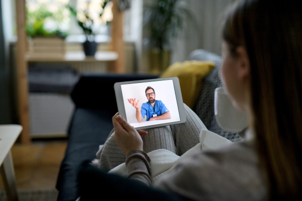 Ill young woman having video call with doctor on tablet at home, online consultation concept.