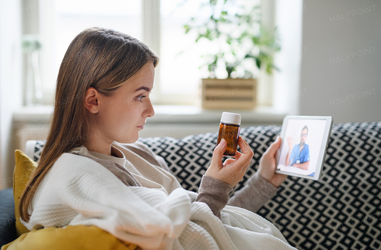 Ill young woman having video call with doctor on tablet at home, online consultation concept.