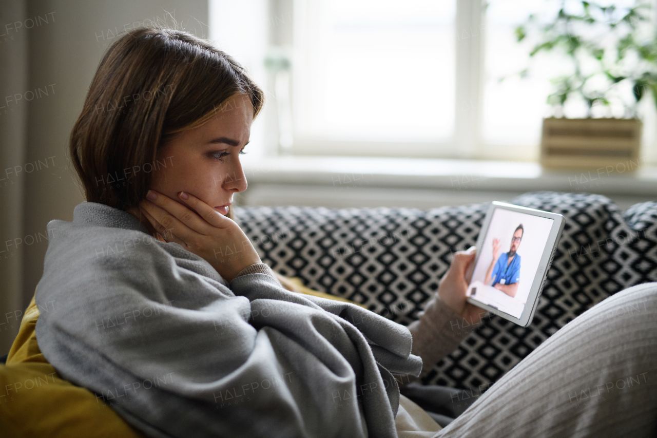 Ill young woman having video call with doctor on tablet at home, online consultation concept.