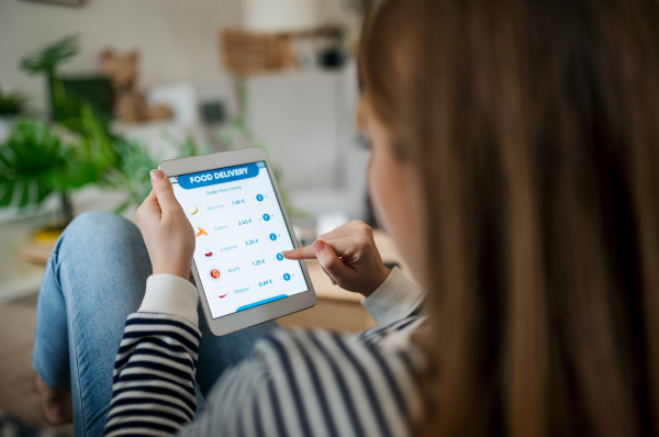 Midsection of unrecognizable woman with tablet ordering food at home, coronavirus and food delivery concept.