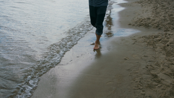 An unrecognizable senior couple running outdoors on beach by sea at the morning.