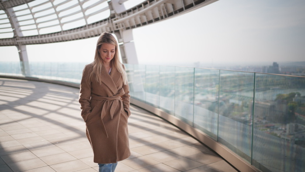 An attractive mid-adult blonde woman walking on bridge with urban view in winter