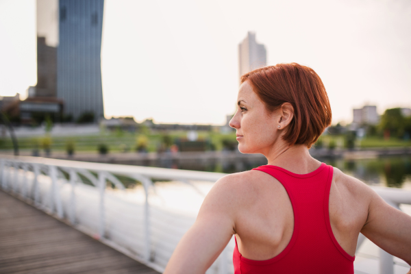 A rear view of young woman runner in city, resting. Copy space.