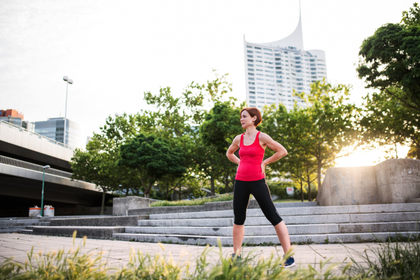 A young woman standing outdoors in city, resting after exercise.