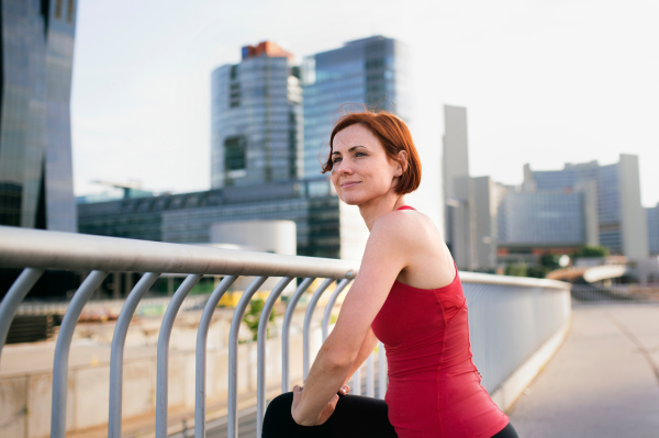 Young woman runner with earphones in city, stretching on the bridge. Copy space.