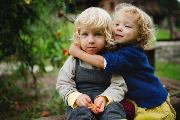 Happy small children sitting outdoors in garden, sustainable lifestyle concept.