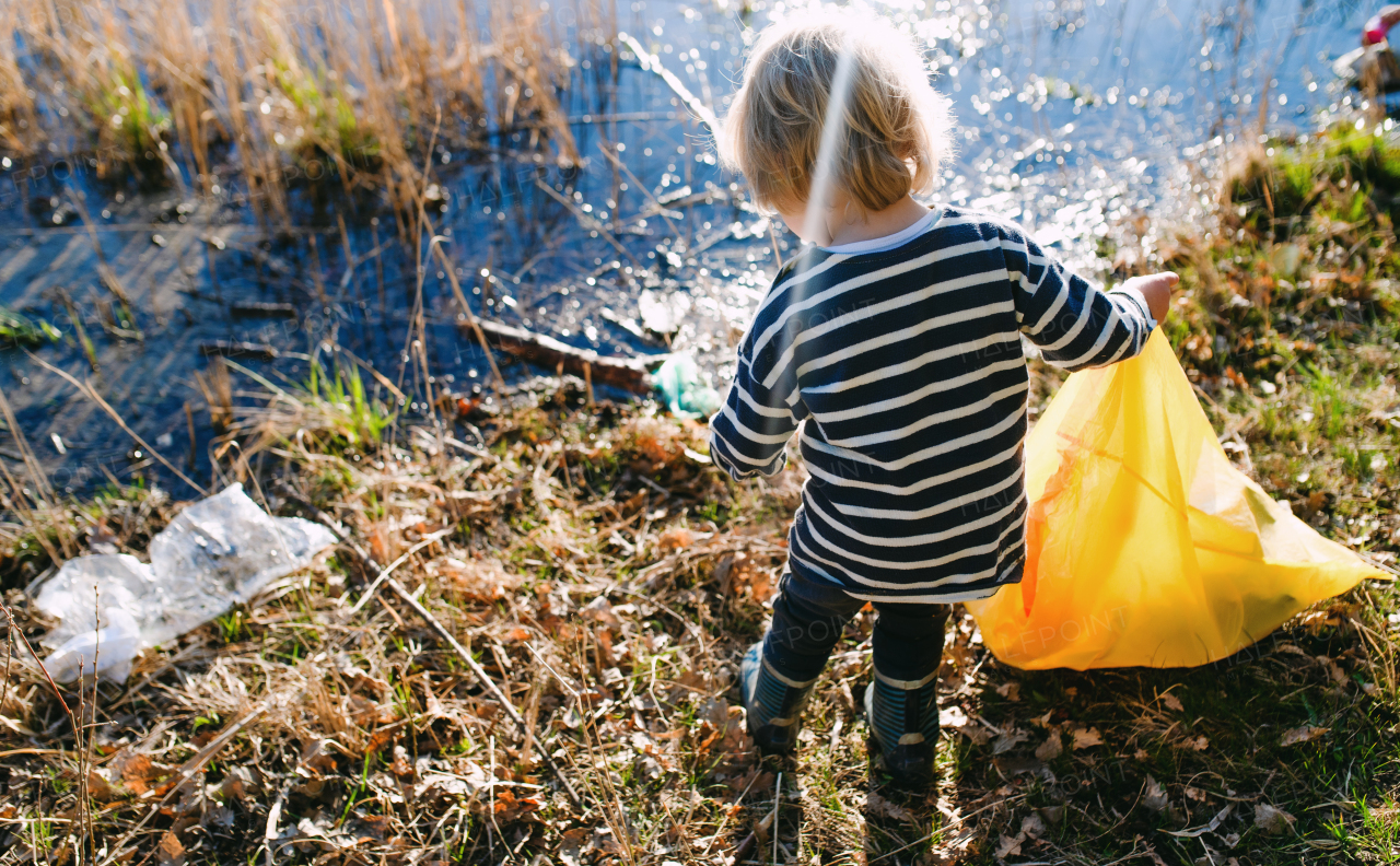 Midsection of unrecognizable small child collecting rubbish outdoors in nature, plogging concept.