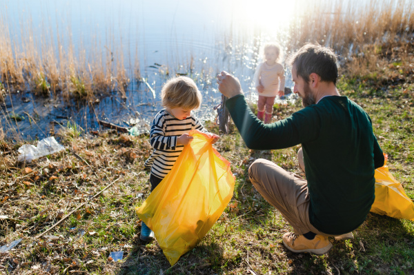 Mature father with small kids working outdoors in garden, sustainable lifestyle concept.