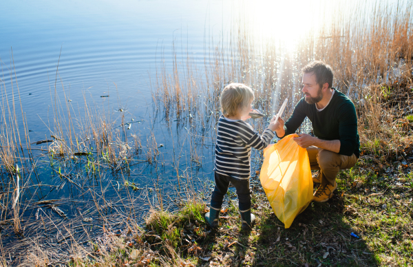 Mature father with small children working outdoors in garden, sustainable lifestyle concept.