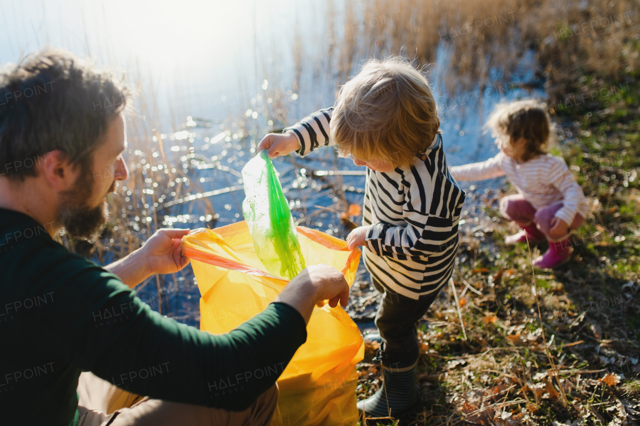 Mature father with small kids working outdoors in garden, sustainable lifestyle concept.