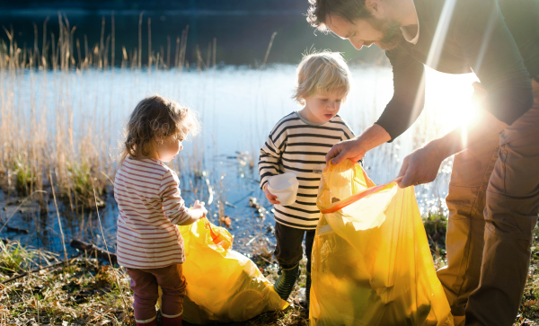 Mature father with small kids working outdoors in garden, sustainable lifestyle concept.