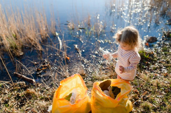 A top view of small child collecting rubbish outdoors in nature, plogging concept.