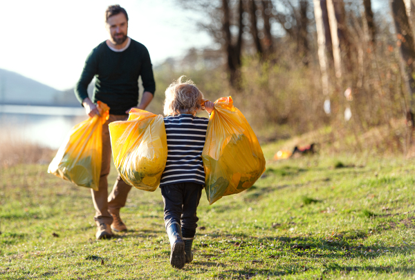 Mature father with small children working outdoors in garden, sustainable lifestyle concept.