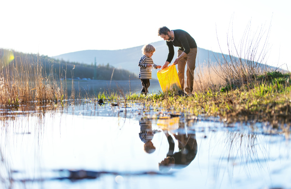 Mature father with small son working outdoors in garden, sustainable lifestyle concept.