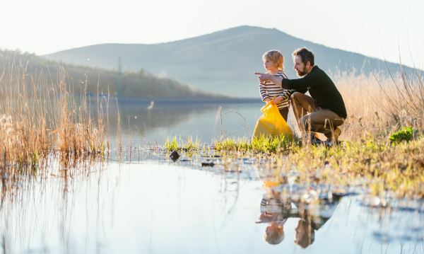 Mature father with small children working outdoors in garden, sustainable lifestyle concept.