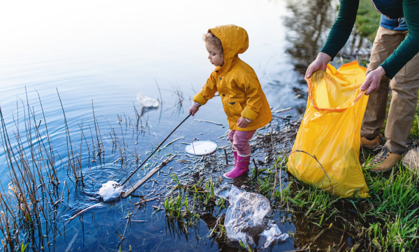 Unrecognizable father with small daughter working outdoors in garden, sustainable lifestyle concept.