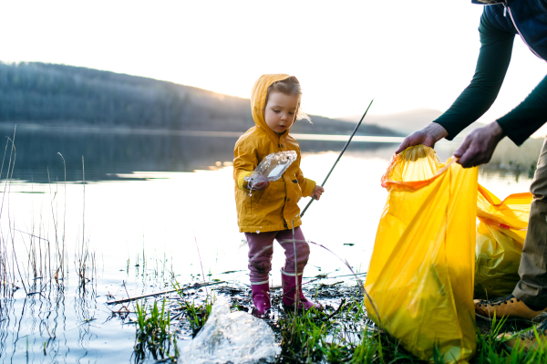 Unrecognizable father with small daughter working outdoors in garden, sustainable lifestyle concept.