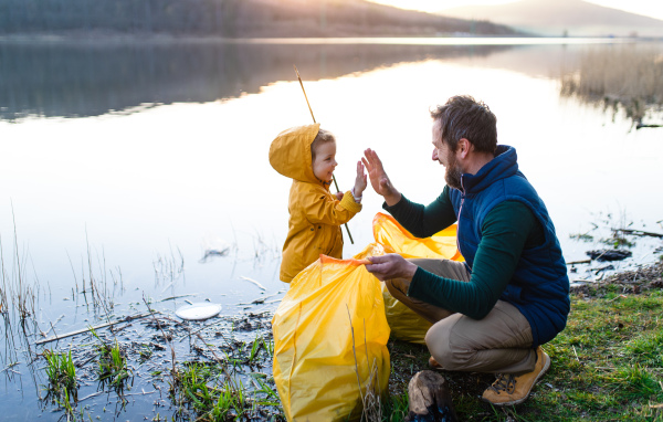 Unrecognizable father with small daughter working outdoors in garden, sustainable lifestyle concept.