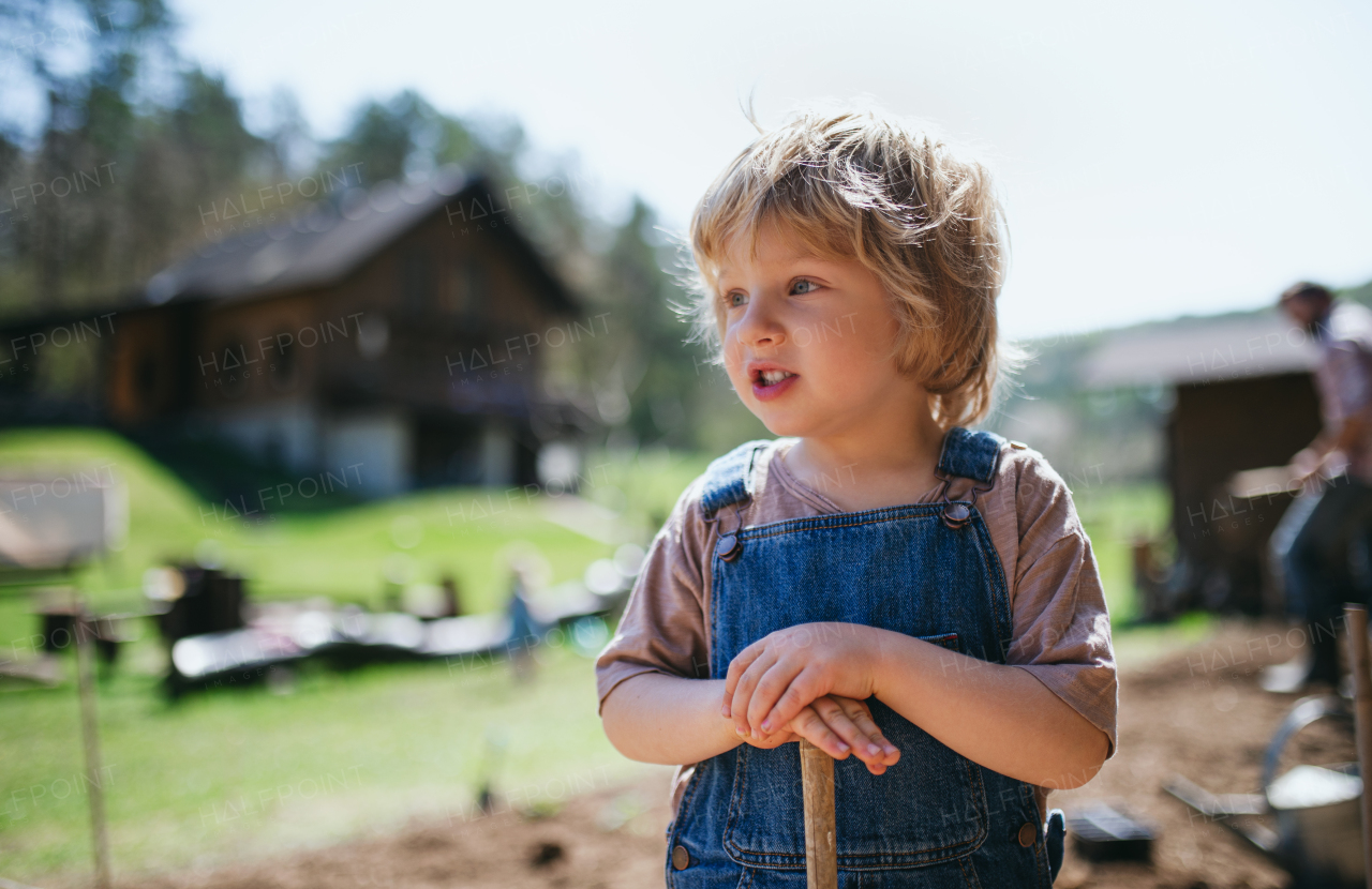 Happy small boy working outdoors in garden, sustainable lifestyle concept.