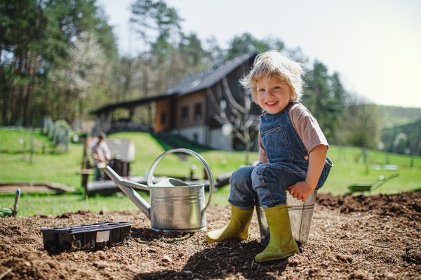 Happy small boy working outdoors in garden, sustainable lifestyle concept.