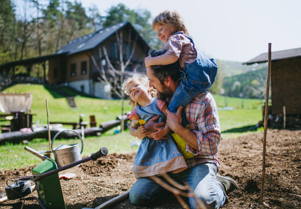 Mature father with small children working outdoors in garden, sustainable lifestyle concept.