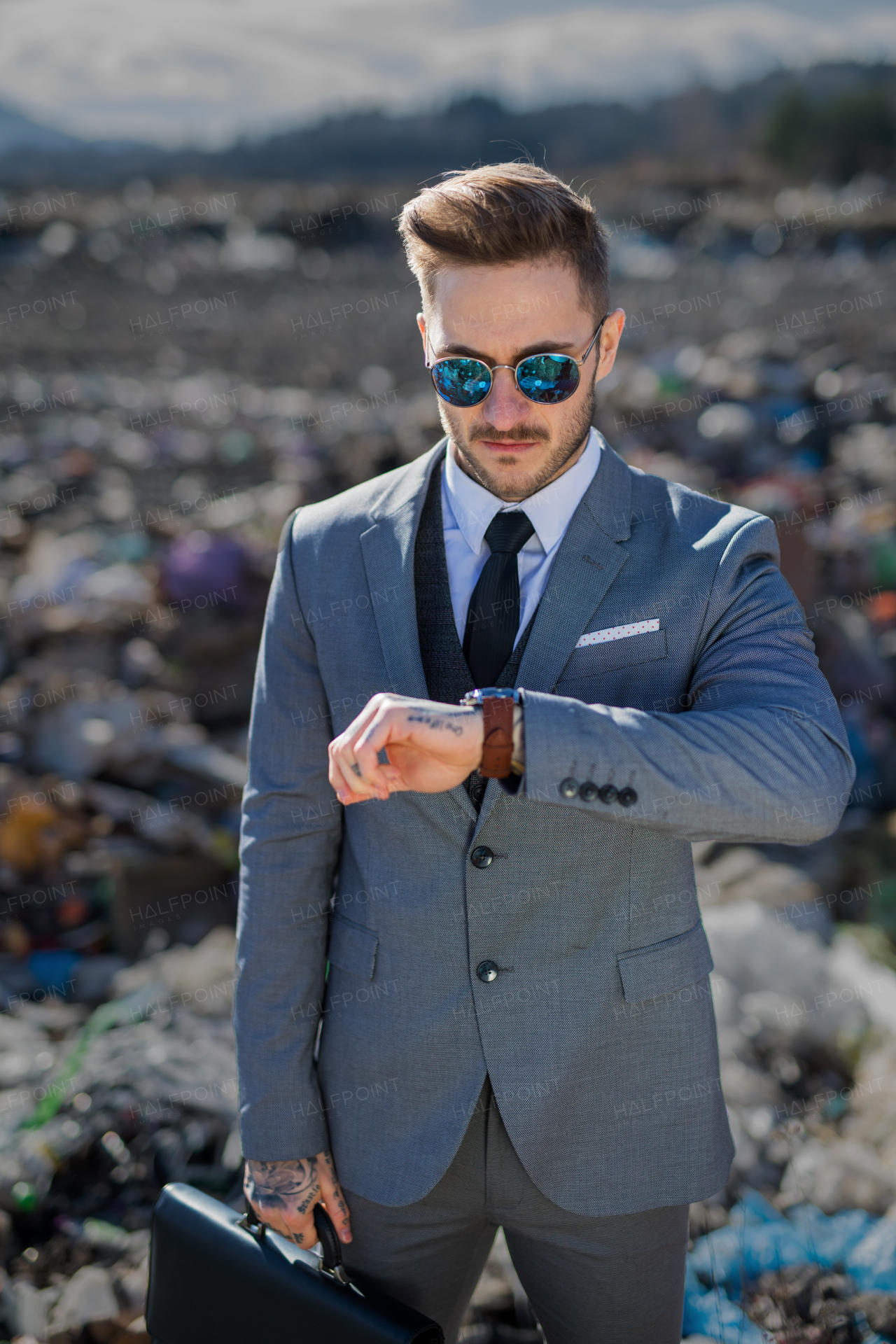 Fashionable modern businessman on landfill, consumerism versus pollution concept.