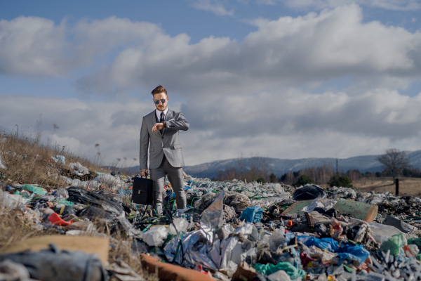 Fashionable modern businessman on landfill, consumerism versus pollution concept.