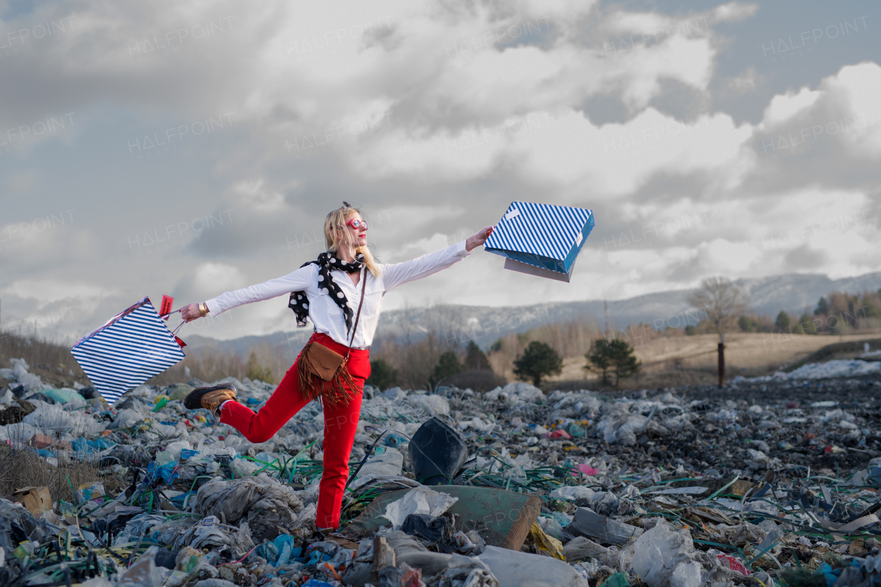 Fashionable modern woman on landfill, consumerism versus pollution concept.