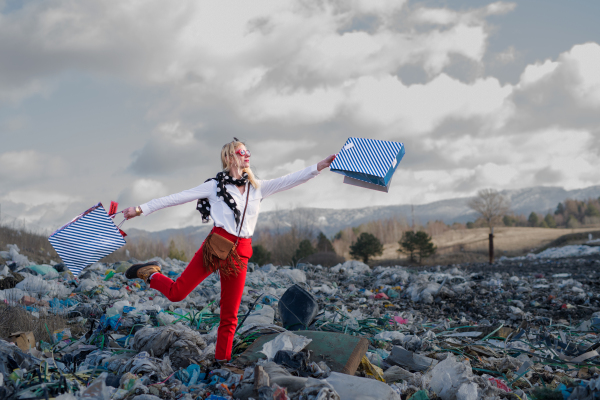 Fashionable modern woman on landfill, consumerism versus pollution concept.