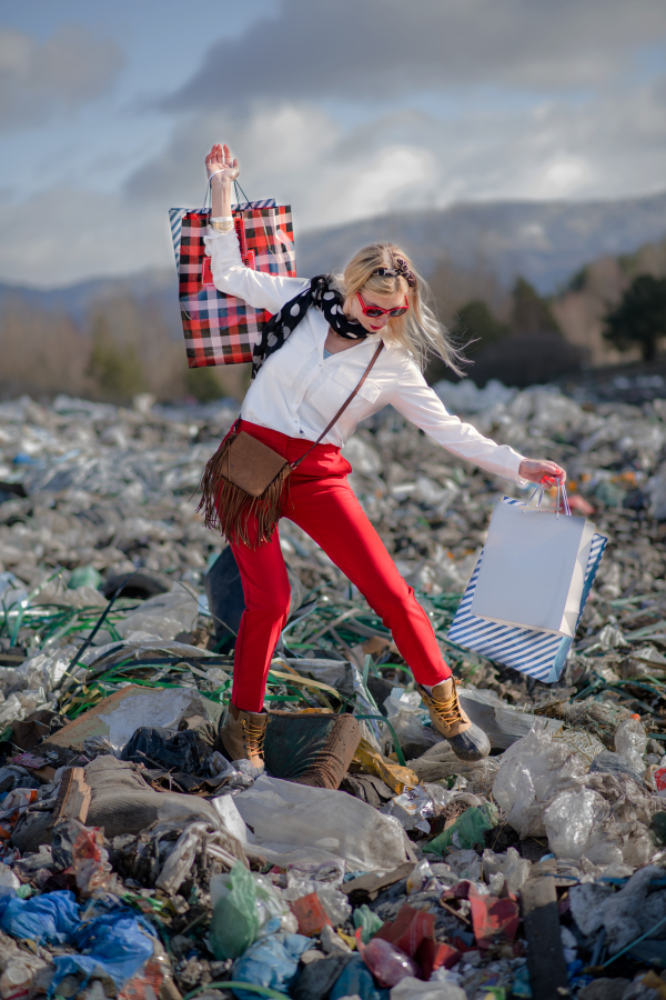 Fashionable modern woman on landfill, consumerism versus pollution concept.