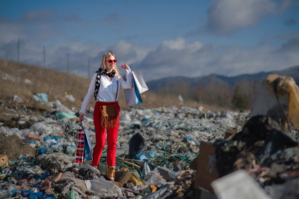 Fashionable modern woman on landfill, consumerism versus pollution concept.