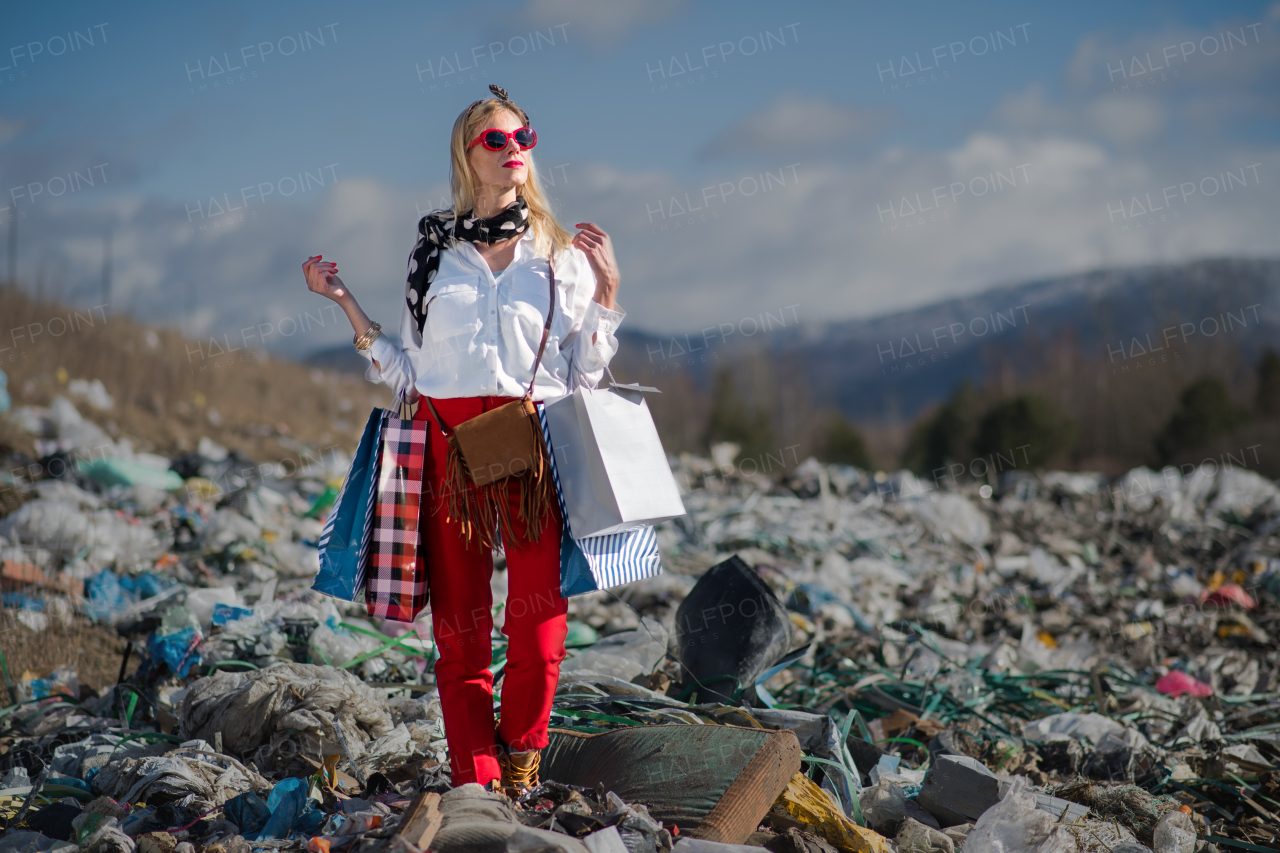 Fashionable modern woman on landfill, consumerism versus pollution concept.