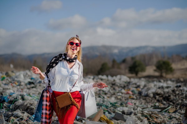 Fashionable modern woman on landfill, consumerism versus pollution concept.