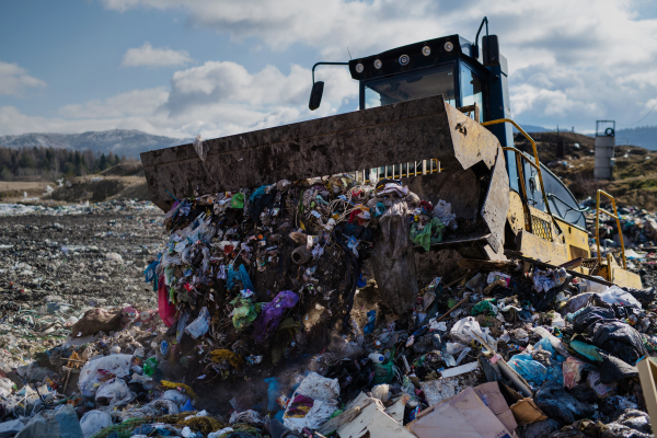 Garbage truck unloading waste on landfill, environmental concept. Copy space.