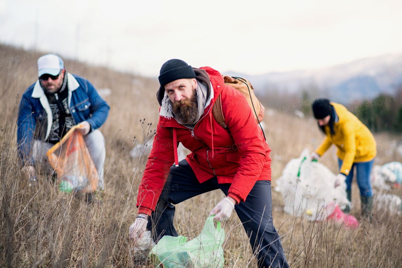 Group of activists picking up litter in nature, environmental pollution and plogging concept.