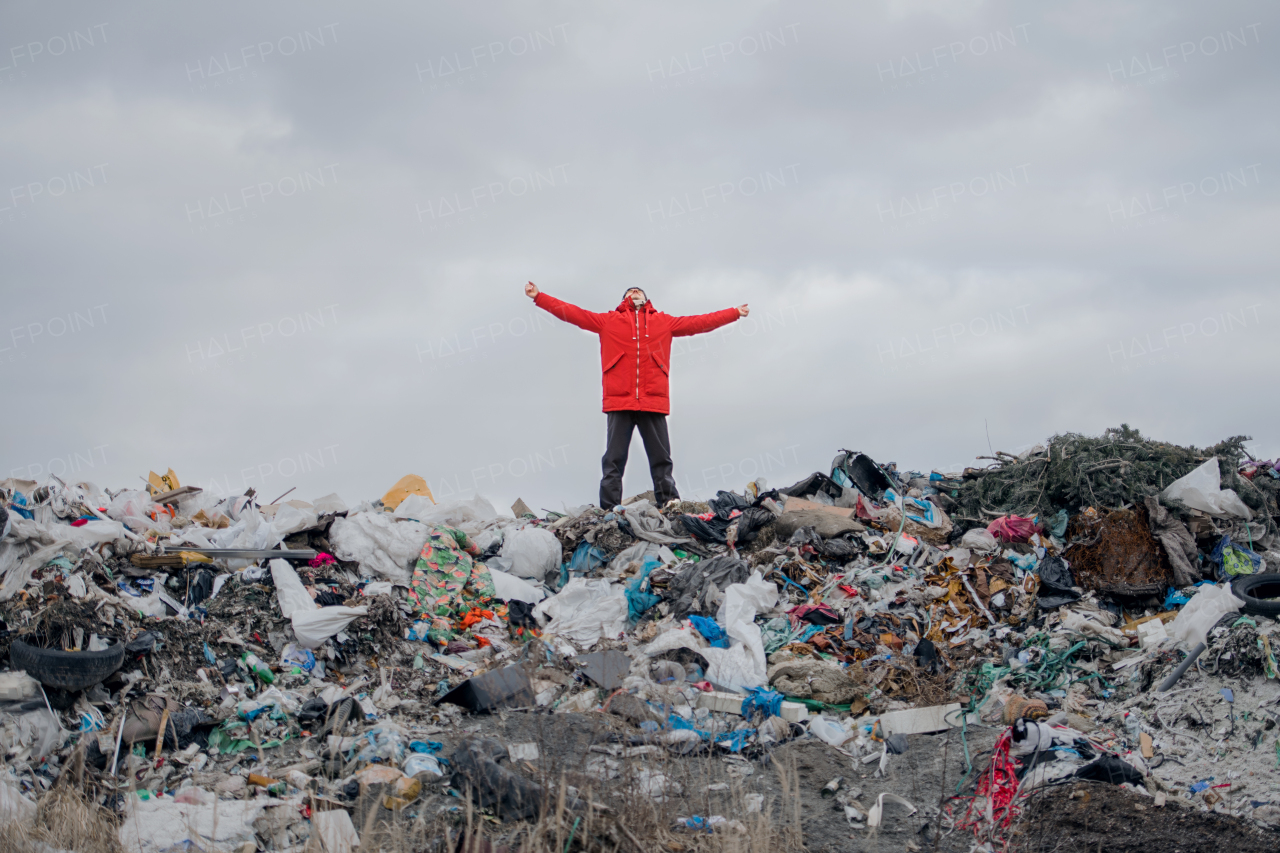 Man with stretched arms standing and looking up on landfill, environmental concept.