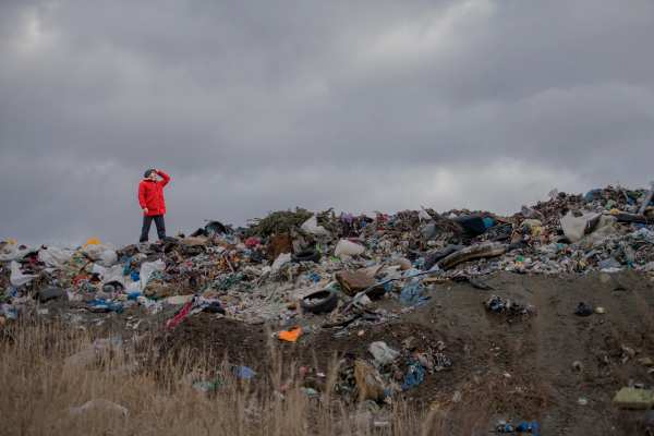 Man standing and looking into distance on landfill, environmental concept. Copy space.