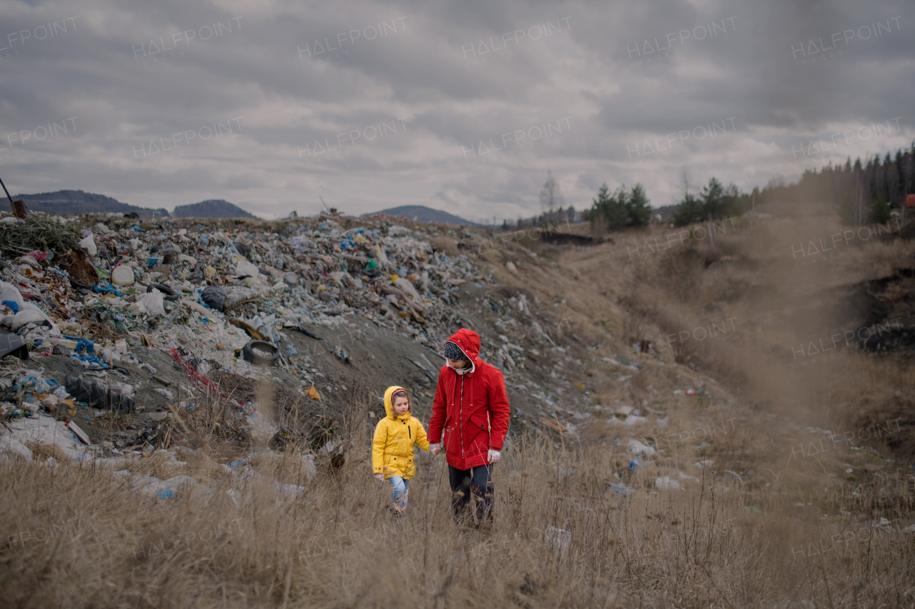 Front view of father with small daughter activist walking on landfill, environmental concept.