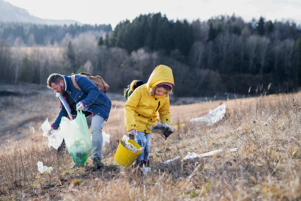 Small child with group of activists picking up litter in nature, environmental pollution concept.