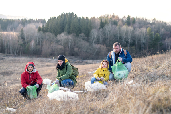 Group of activists picking up litter in nature, environmental pollution and plogging concept.