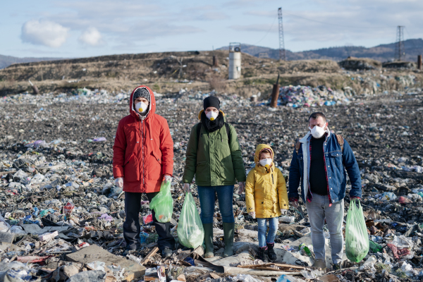 Group of activists with face masks standing on landfill, environmental pollution concept.