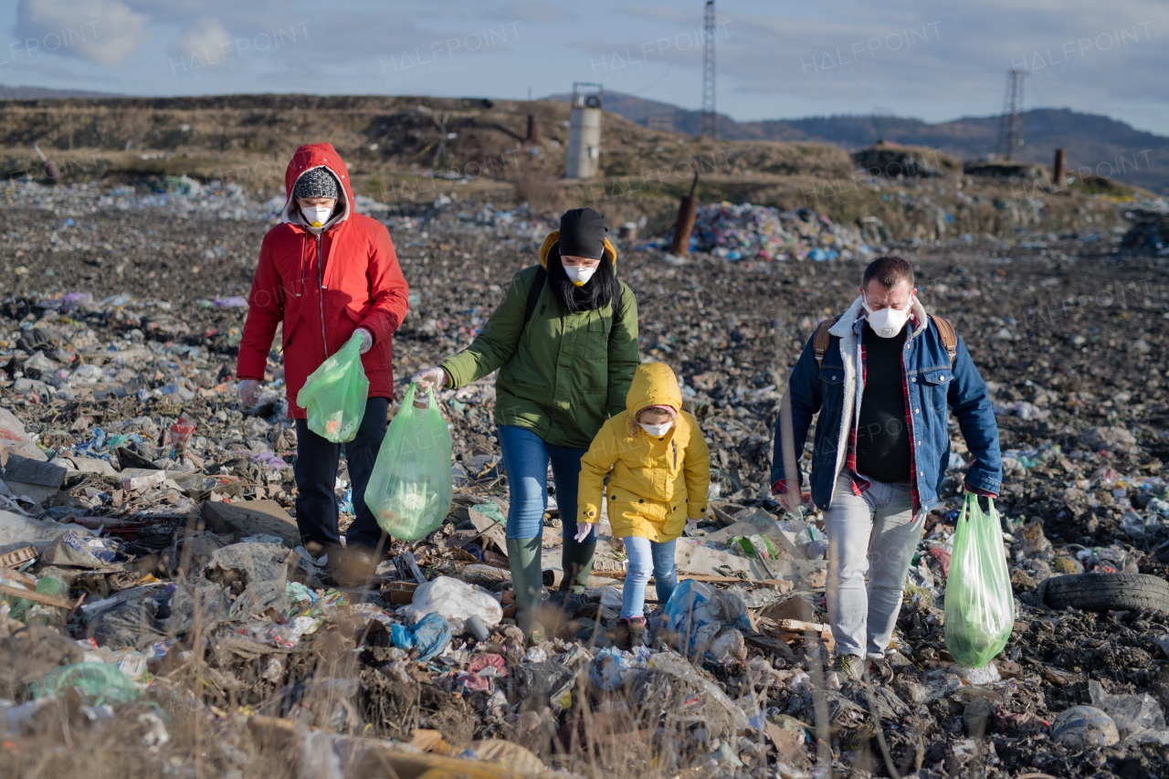 Group of activists with face masks standing on landfill, environmental pollution concept.