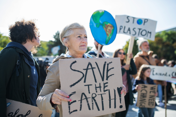 A senior with placard and poster on global strike for climate change.