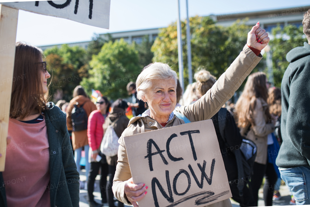 A senior woman with placard and poster on global strike for climate change.