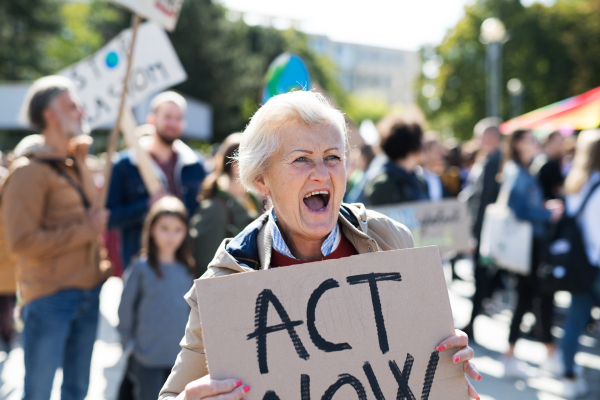 A senior with placard and poster on global strike for climate change, shouting.