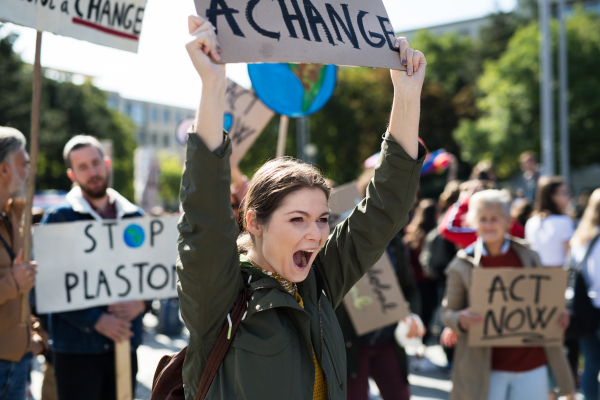 Young woman with placard and poster on global strike for climate change, shouting.